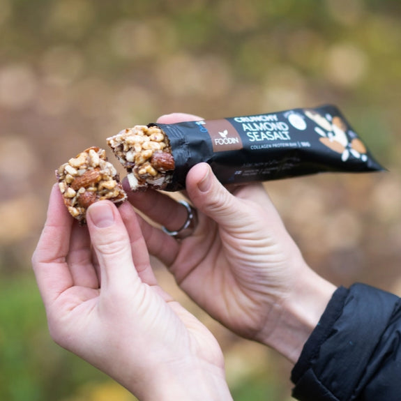 Hånd holder Crunchy Almond Seasalt proteinbar med nødder og mandler