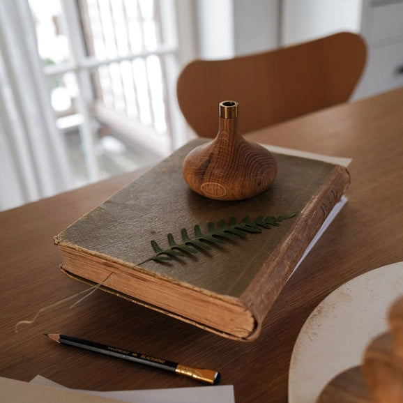 En tidløs lysestage i egetræ med minimalistisk messing detalje – skabt til ro, varme og naturlig elegance.